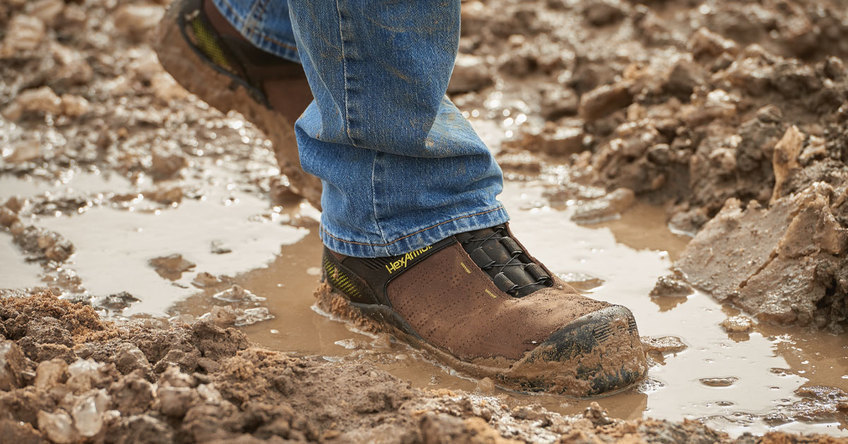 Xbase brown boat boot standing in a muddy puddle showing water resistance. 