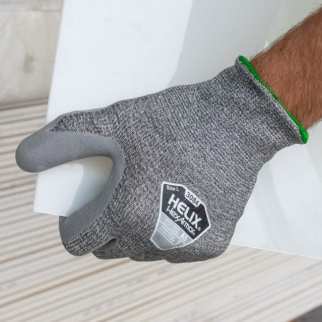 Hands wearing the Helix 3084 abrasion-resistant gloves while handling a glass sheet.