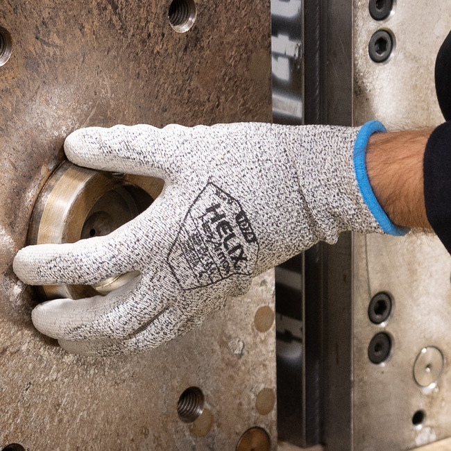A hand wearing Helix 1074 abrasion-resistant gloves while adjusting a metal gasket.