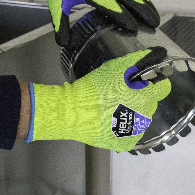 Hands wearing the Helix 3060 hi-vis work gloves handing sharp sheet metal scraps.