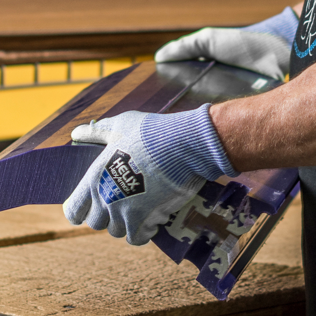 Hands wearing Helix 2085 cut-resistant gloves handling an object with sharp edges.