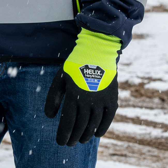 A worker wearing the Helix 2059 hi-vis winter gloves outdoors while it is snowing. 