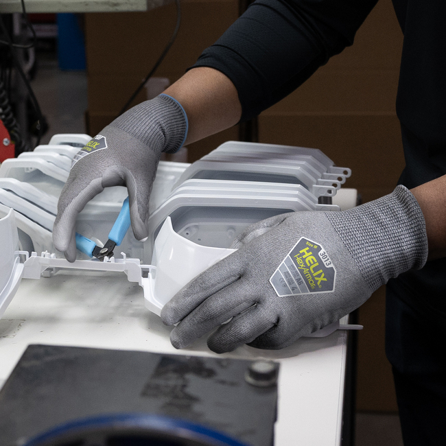 Worker wearing the Helix 3013 puncture-resistant gloves while using a tool to cut a piece of plastic.
