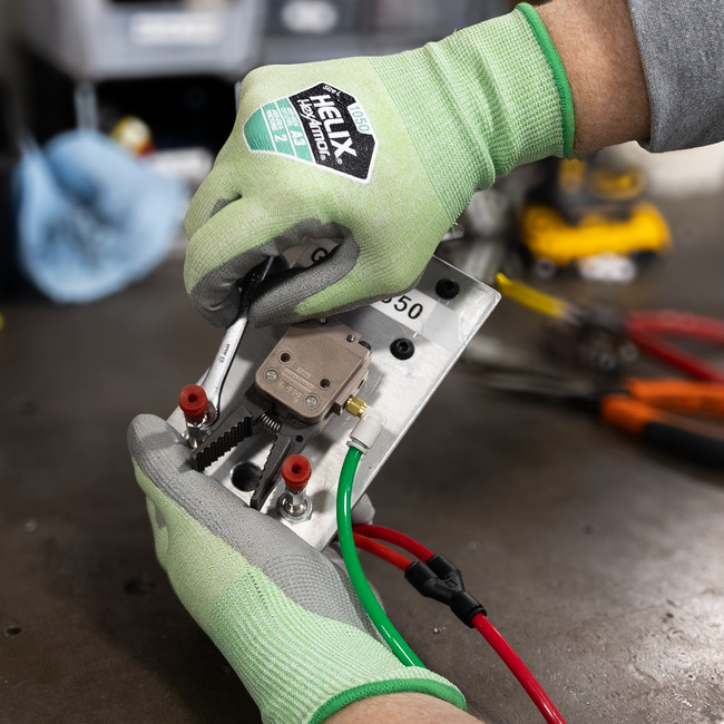 Hands wearing the fiberglass-free and steel-free Helix 1050 general purpose gloves while handing a metal circuit and wiring.